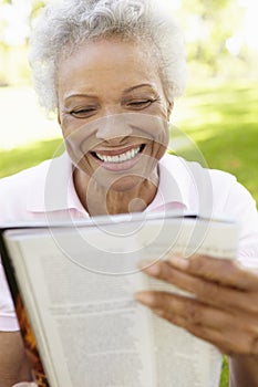 Senior African American Woman Reading Magazine In Park