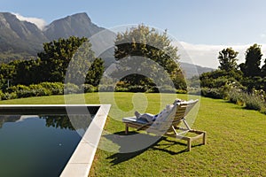 Senior african american woman relaxing in deckchair by swimming pool in sunny garden