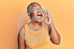 Senior african american woman wearing casual style with sleeveless shirt shouting and screaming loud to side with hand on mouth