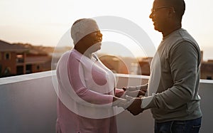 Senior african couple dancing outdoors at summer sunset - Focus on woman face