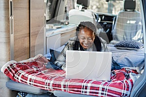 Senior african woman having fun inside camper van using laptop computer - Focus on face