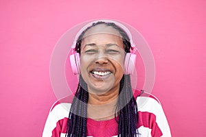 Senior african woman listening playlist music with headphones - Focus on face