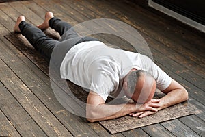 Senior aged man resting after yoga exercise on floor. Sports at home for health. photo