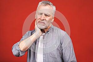 Senior aged man suffering from toothache on red background