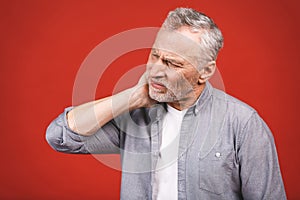 Senior aged man suffering from toothache on red background