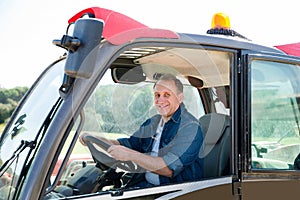 Senior aged man working on small farm tractor