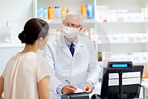 Senior apothecary in mask and customer at pharmacy