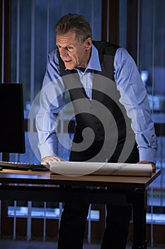 Senior architect or engineer standing at his desk looking at computer screen