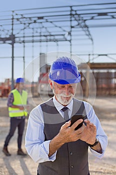Senior architect with phone at building site