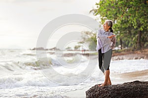 Senior Asia woman stretching on the beach