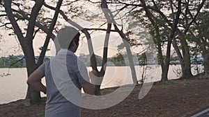 Senior asian athlete woman with wireless headphone running in urban city trees park during evening sunset. elderly active female j