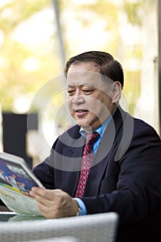 Senior Asian businessman reading newspaper