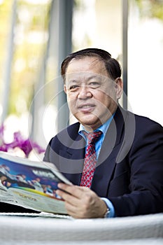 Senior Asian businessman reading newspaper