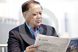 Senior Asian businessman reading newspaper