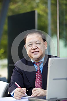 Senior Asian businessman writing proposal