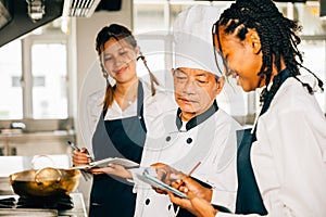 Senior Asian chef in a restaurant kitchen educates multiracial students