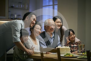 Senior asian couple celebrating wedding annversary with three generational family