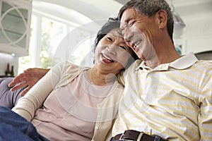 Senior Asian Couple At Home Relaxing On Sofa Together