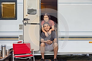 Senior asian couple joyful and relax sitting in front of caravan home on vacation