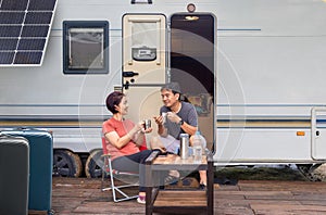 Senior asian couple joyful and relax sitting in front of caravan home on vacation