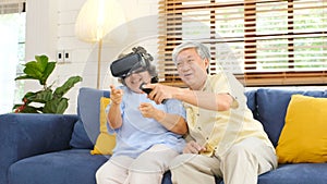Senior asian couple playing virtual reality headset and using digital tablet in home living room with happiness emotion,