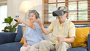 Senior asian couple playing virtual reality headset and using digital tablet in home living room with happiness emotion,