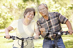 Senior Asian couple riding bikes in park