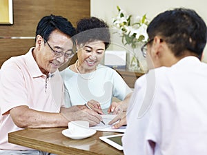 Senior asian couple signing a contract