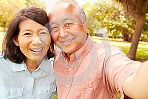 Senior Asian Couple Taking Selfie In Park Together