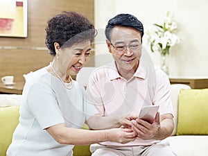 Senior asian couple using mobile phone