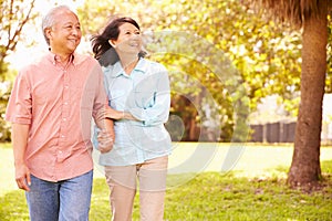 Senior Asian Couple Walking Through Park Together