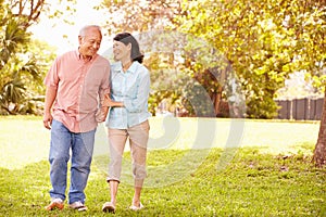 Senior Asian Couple Walking Through Park Together photo