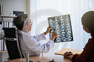 Senior asian doctor examine MRI picture explain to patient.