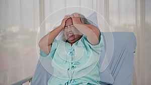 Senior Asian female patient with headache on a bed in hospital