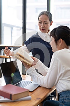 Senior Asian female teacher helping and explaining difficult math problems to her student