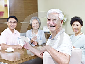 Senior asian man in playing cards with friends