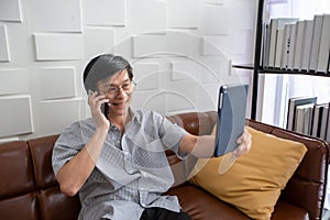 Senior Asian man playing tablet and video call on sofa in living room at home  Portrait of Asian elderly man is Relaxing and