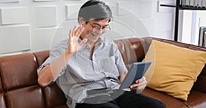 Senior Asian man playing tablet and video call on sofa in living room at home  Portrait of Asian elderly man is Relaxing and