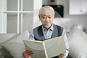 Senior asian man reading a book at home