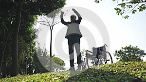 Senior asian man standing up from wheel chair stretching arms