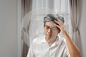 Senior asian man suffering from headache at home photo