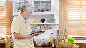 Senior asian man using digital tablet at home background, Elderly asia male and digital tablet standing in kitchen, Active old