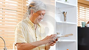 Senior asian man using smartphone at home background, Happy retirement asia male holding phone while standing in kitchen, Active