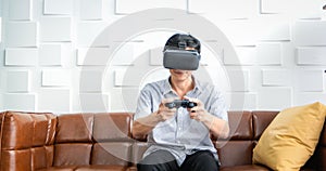 Senior Asian man using tablet and virtual reality simulator playing games in living room and feeling happy . Lifestyle Senior