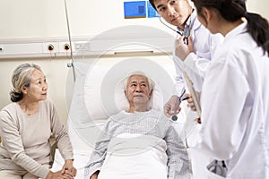 Senior asian patient being check by doctors in hospital ward