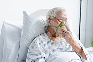 Senior asian patient holding oxygen mask