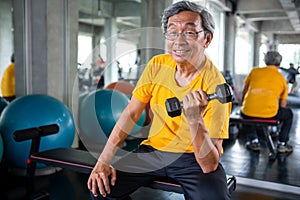 Senior asian sport man lifting dumbbells in fitness gym . elder male exercising ,  working out , training weights, healthy ,