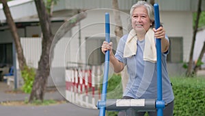 Senior Asian woman in casual workout in exercise stations in public park. Represents keeping young with physical activity, Open
