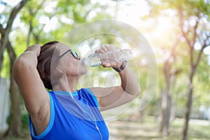 Senior asian woman drinking water bottle after work out exercising