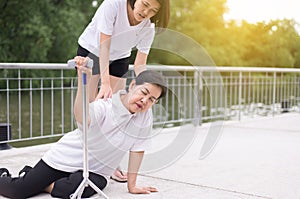 Senior asian woman with faint sitting on floor after falling down,female take care and support